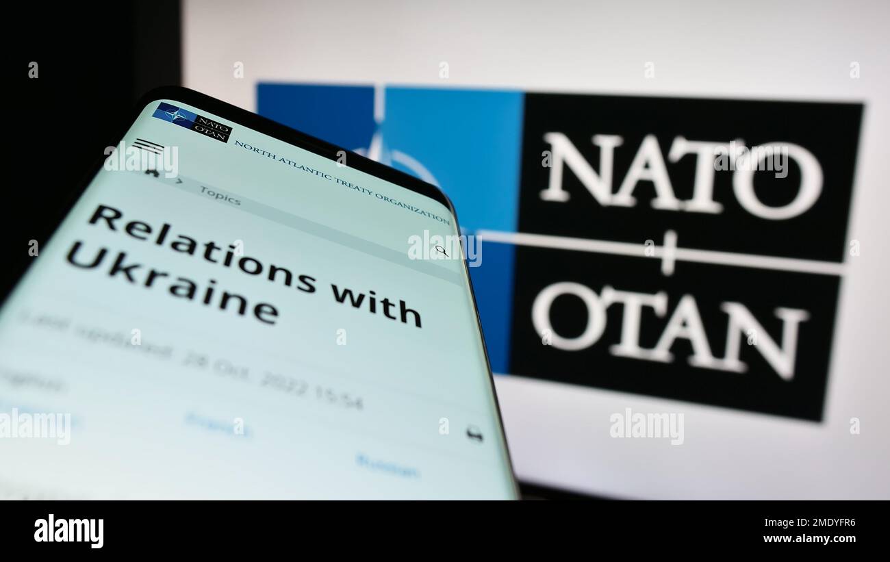 Mobiltelefon mit Webseite der Nordatlantischen Vertragsorganisation (NATO) auf dem Bildschirm vor dem Logo. Fokus auf oberer linker Seite des Telefondisplays. Stockfoto