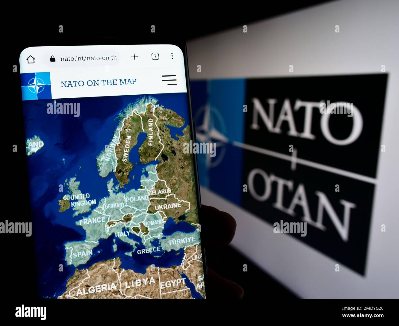 Person mit Smartphone und Website der NATO auf dem Bildschirm vor dem Logo. Konzentrieren Sie sich auf die Mitte des Telefondisplays. Stockfoto