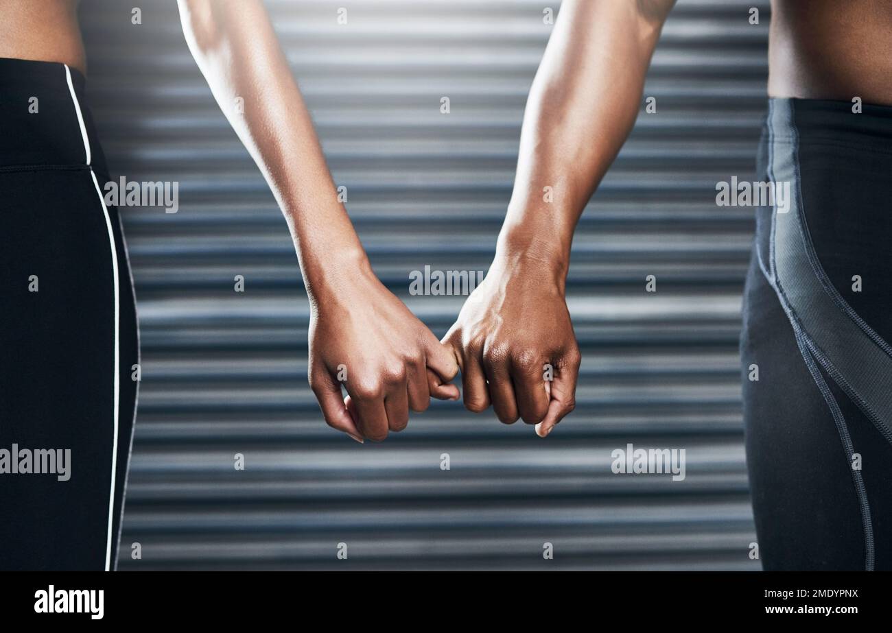 Ich vertraue darauf, dass du diese Reise mit mir durchziehst. Nahaufnahme eines sportlichen Paares, das sich mit dem kleinen Finger vor grauem Hintergrund hält. Stockfoto