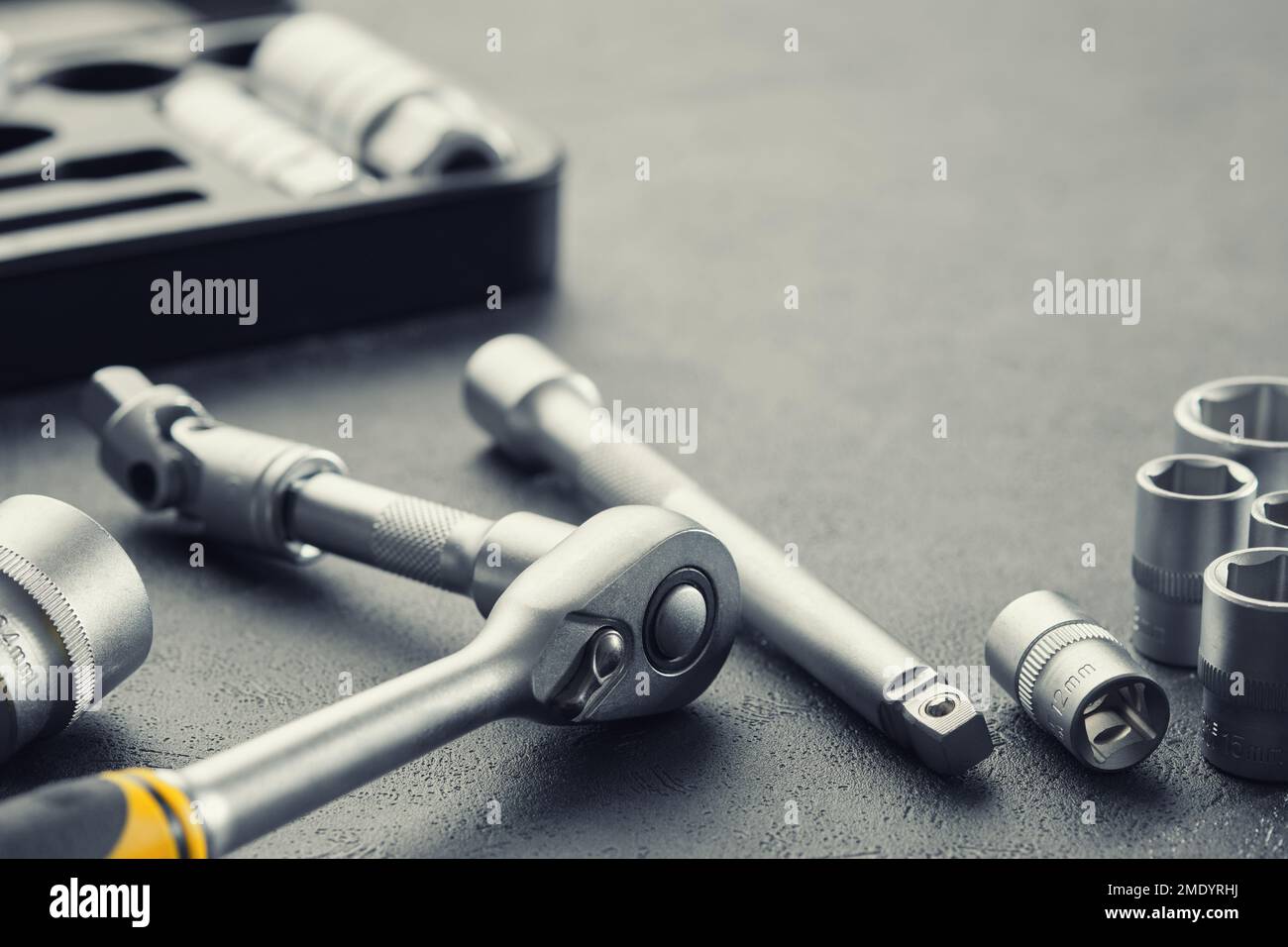 Werkzeugsatz mit Knarre und Bits. Steckschlüssel und Ratschenköpfe. Werkzeugsatz für das Auto im Hintergrund. Ausrüstung für Kfz-Mechaniker für Kfz-Reparatur im Service Stockfoto