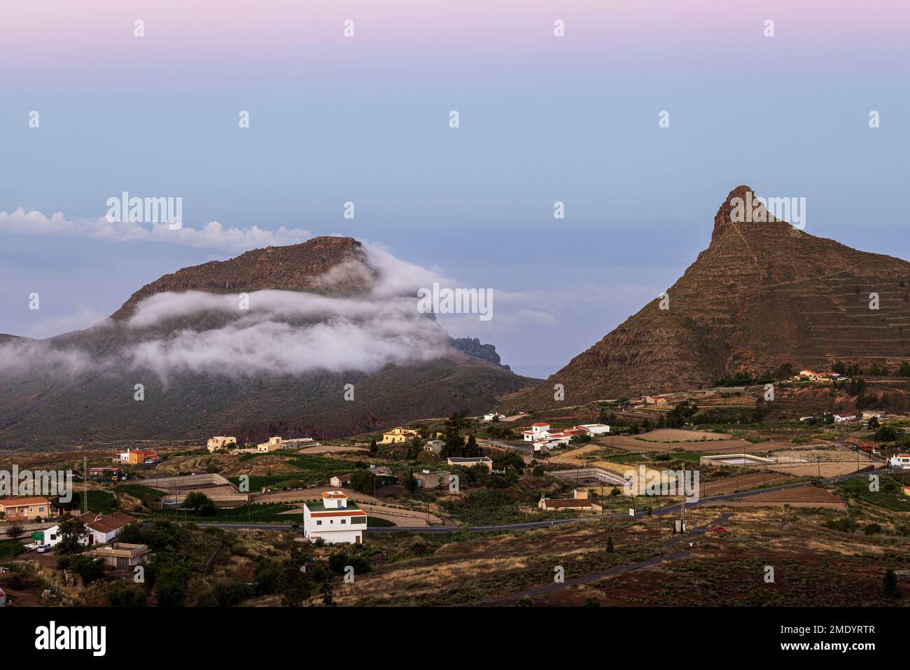 Blick über das Dorf Ifonche zu den Küstenresorts Los Cristianos und Las Americas bei Sonnenaufgang mit Vollmond-Kulisse im Westen, Adeje, Tene Stockfoto