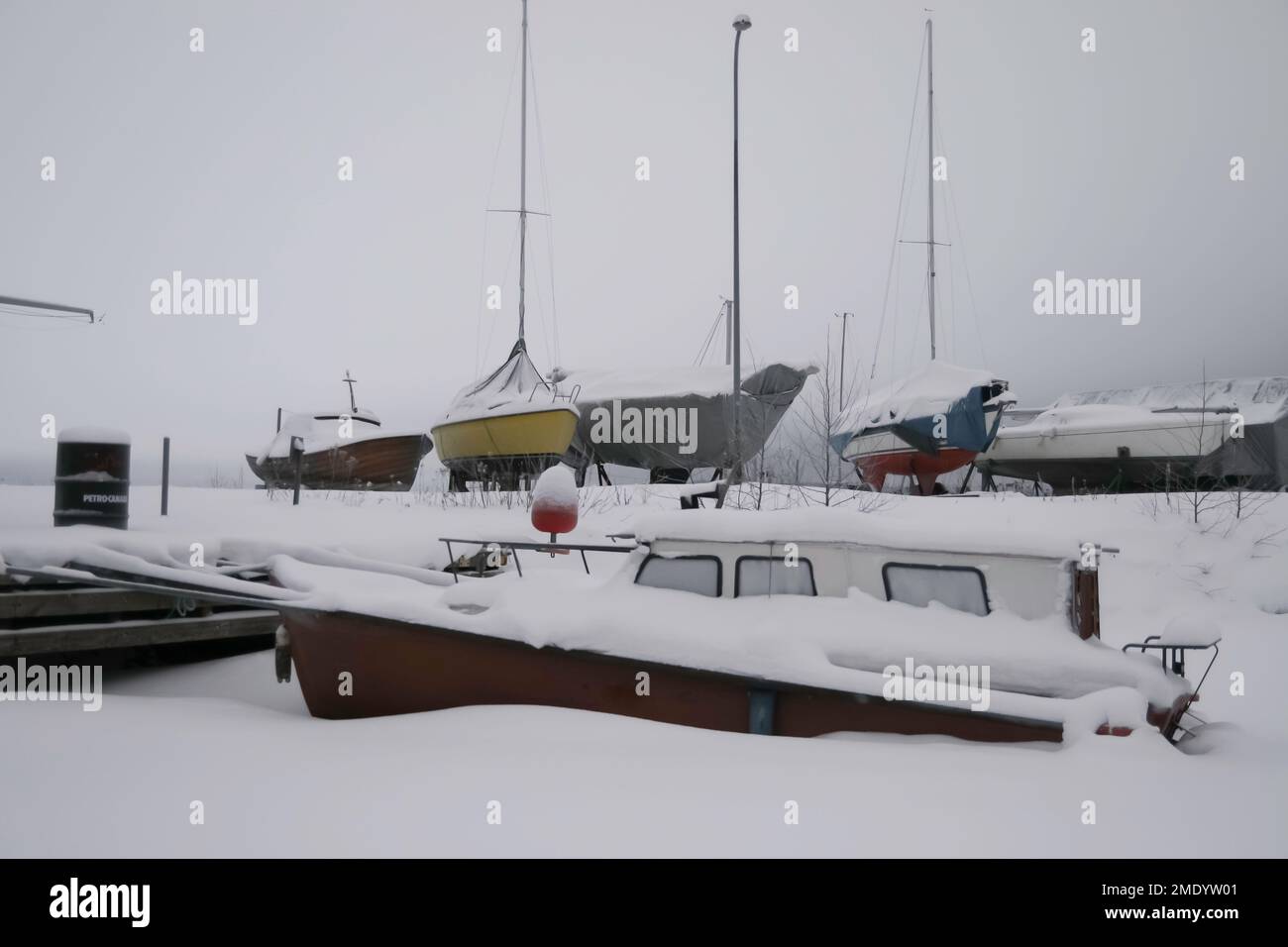 Verschneite Winterfotos in Tampere, Finnland. Die Boote liegen an der Küste und sind mit Schnee und Eis bedeckt. Der Winter ist gekommen und sieht eiskalt aus. Stockfoto