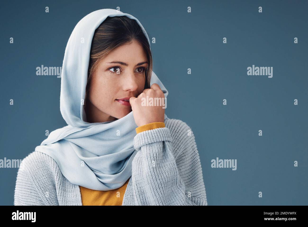 Ich fühle mich nachdenklich. Eine attraktive junge Frau, die aufmerksam aussieht, während sie vor grauem Hintergrund posiert. Stockfoto