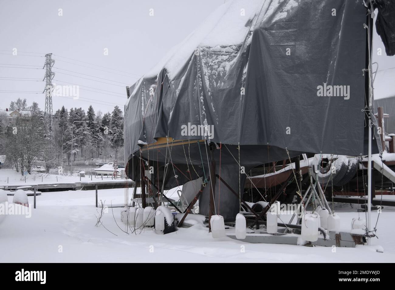 Verschneite Winterfotos in Tampere, Finnland. Die Boote liegen an der Küste und sind mit Schnee und Eis bedeckt. Der Winter ist gekommen und sieht eiskalt aus. Stockfoto