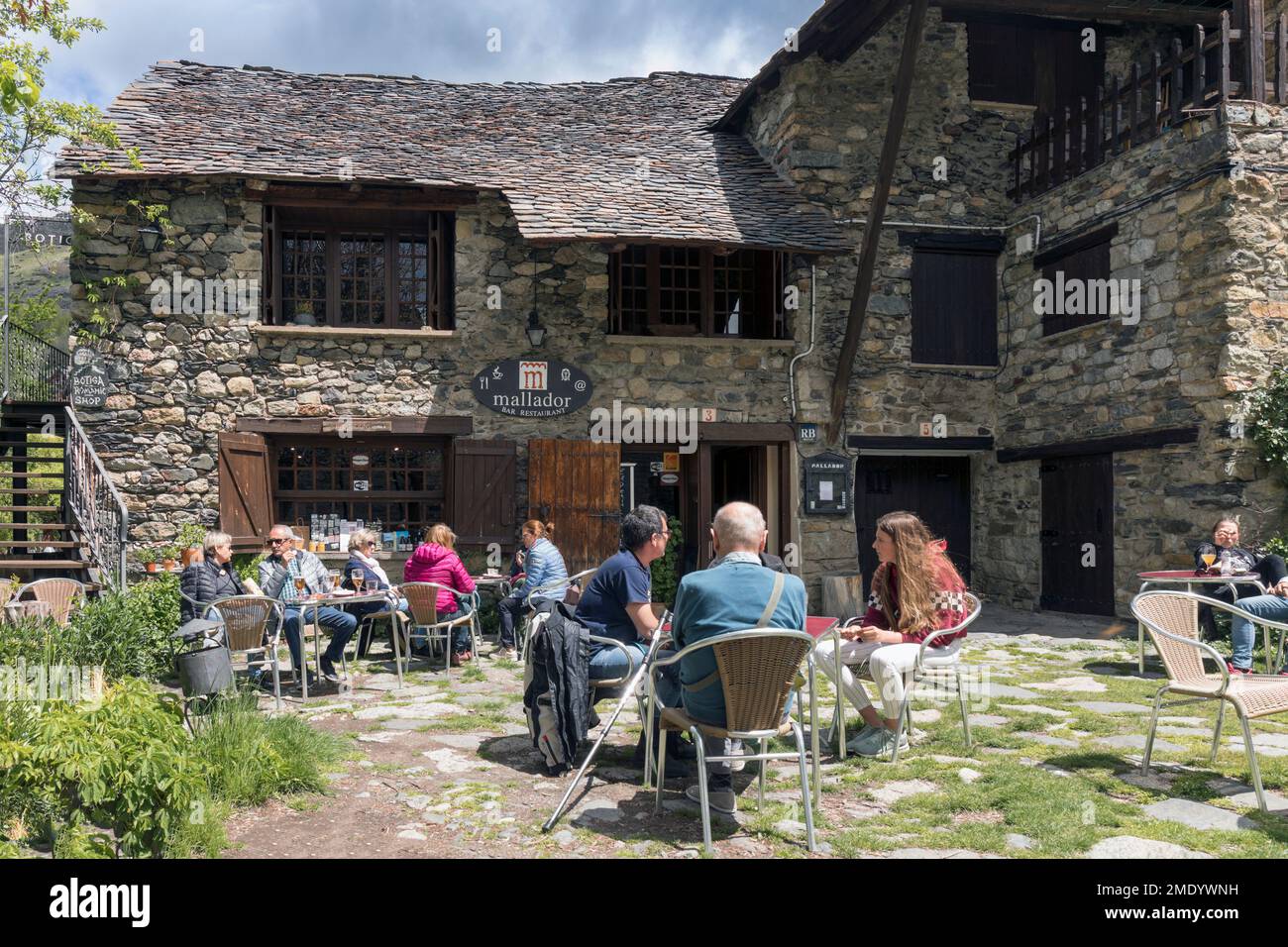 Taüll, Provinz Lleida, Katalonien, Spanien. Gäste auf der Terrasse des Restaurants Mallador neben der romanischen Kirche Sant Climent. Stockfoto