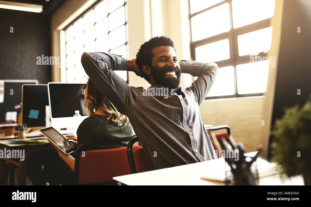 Nutzen Sie die Vorteile, die die Technologie zu bieten hat. Ein gutaussehender Geschäftsmann, der an seinem Schreibtisch in einem modernen Büro sitzt. Stockfoto