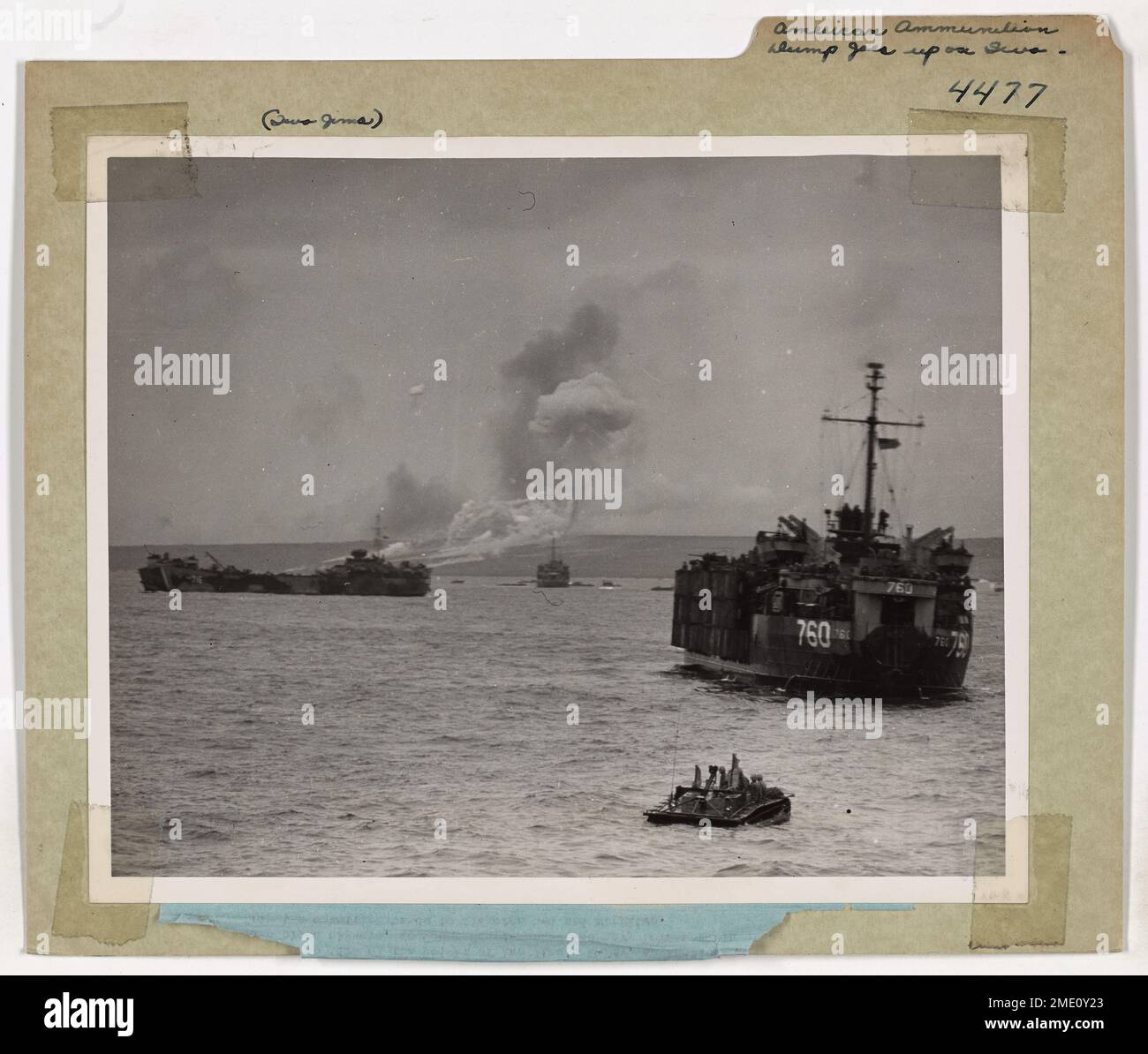 Eine amerikanische Munitionsdeponie explodiert in der Luft, wobei Küstenwache und Marine LSTs in den Strand und aus dem Strand ziehen, um Truppen und Vorräte während einer Kriegsoperation zu liefern. Das Bild fängt das Chaos auf dem Schlachtfeld ein. Stockfoto