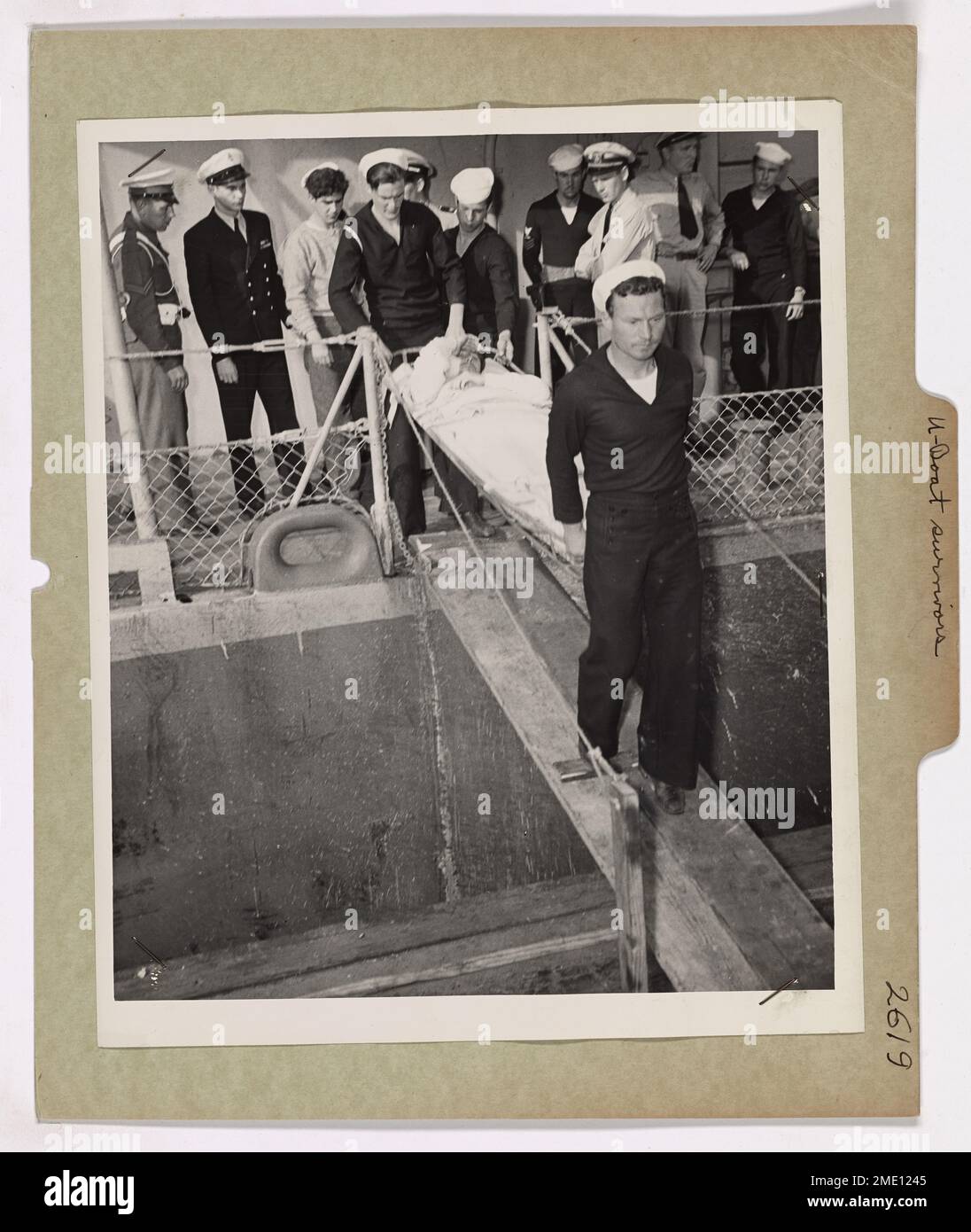 Ein verwundeter Überlebender eines deutschen U-Bootes, das von einem von der Küstenwache bemannten Destroyer Escort versenkt wurde, wird zur medizinischen Behandlung an Land gebracht. Der deutsche U-Boot-Kommandeur, erst 26 Jahre alt, wurde zusammen mit seiner Besatzung gefangen genommen, nachdem ihr Schiff zerstört wurde. Stockfoto