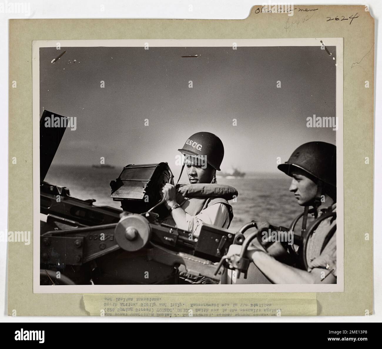 Zwei Ohio Coast Guardsmen stehen an Bord eines von der Küstenwache bemannten Invasionstransportes während der D-Day-Invasion der Normandie an ihren Waffen. Sie waren Teil der kritischen amphibischen Angriffsoperationen. Stockfoto