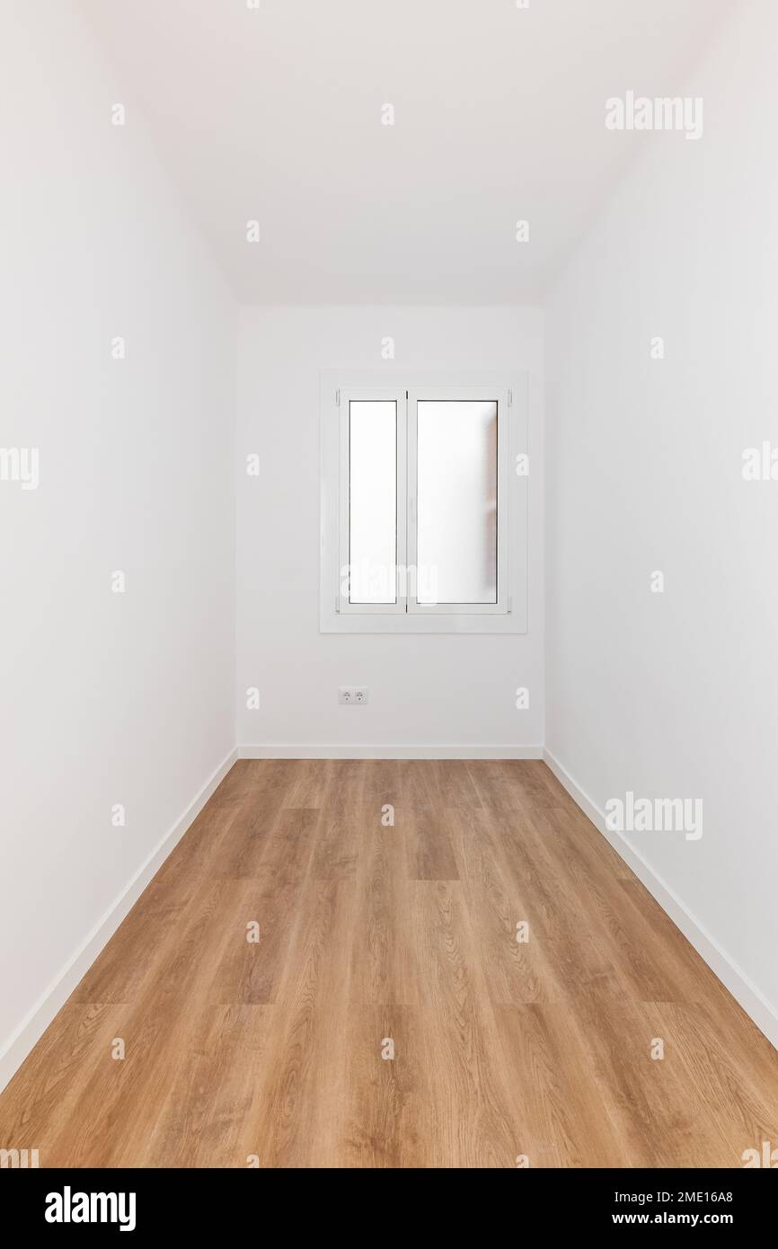 Langer, schmaler, rechteckiger Raum mit weißen Wänden und Holzparkett, gut beleuchtet durch das Milchglasfenster von neugierigen Augen. Mehrere Steckdosen für Stockfoto