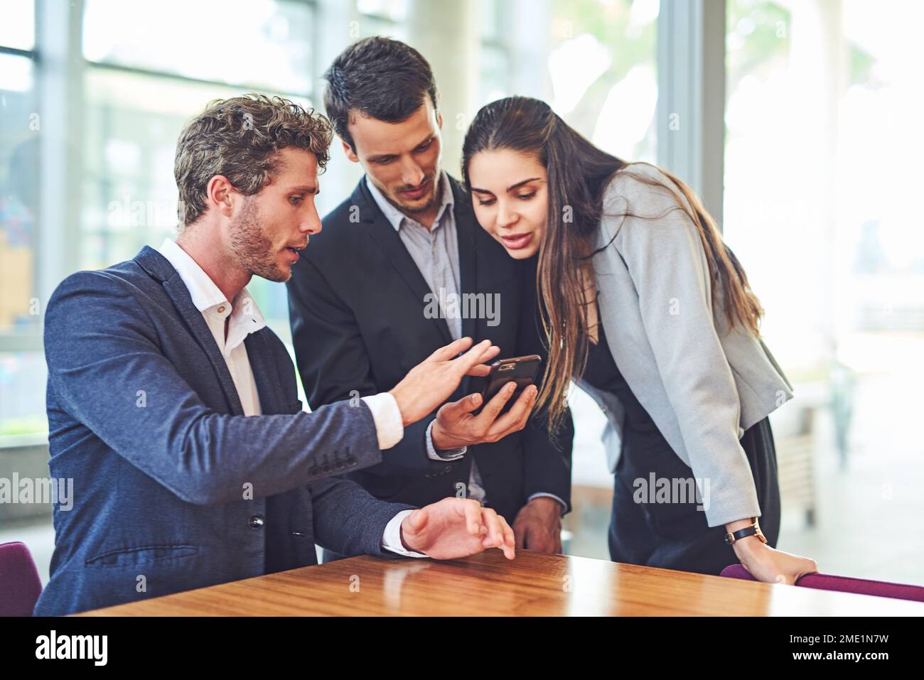 Sehen Sie sich diese aktualisierte Business-App an. Geschäftsleute, die im Haus ein Handy benutzen. Stockfoto