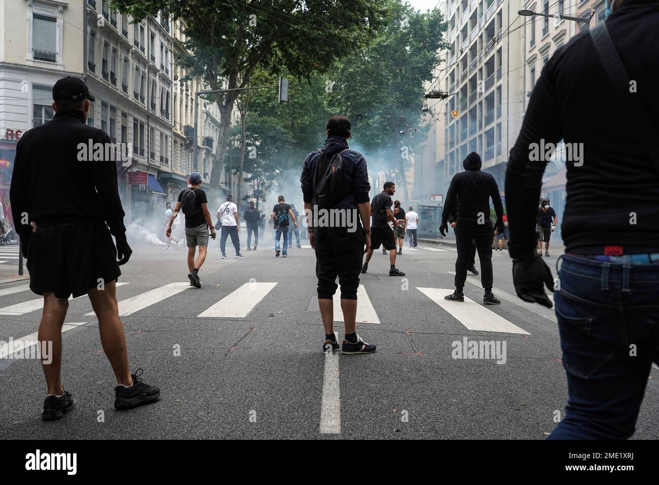 Protestors stand in smoke flares in front of policemen during a demonstration in Lyon, central France, Saturday, July 31, 2021. Demonstrators gathered in several cities in France on Saturday to protest against the COVID-19 pass, which grants vaccinated individuals greater ease of access to venues. (AP Photo/Laurent Cipriani) Stockfoto