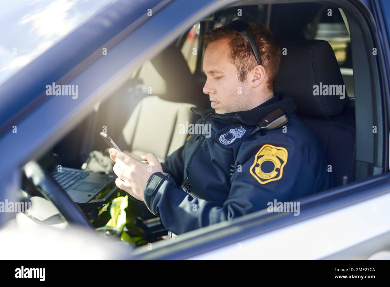 Kommunikation ist der Schlüssel zur Sicherheit. Ein gutaussehender junger Polizist, der sein Handy benutzte, während er auf Patrouille war. Stockfoto