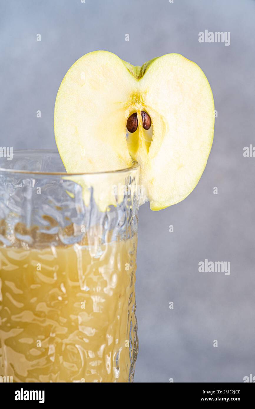 Frischer Apfel-Smoothie, serviert in Glas mit Apfelscheiben auf Betonhintergrund Stockfoto