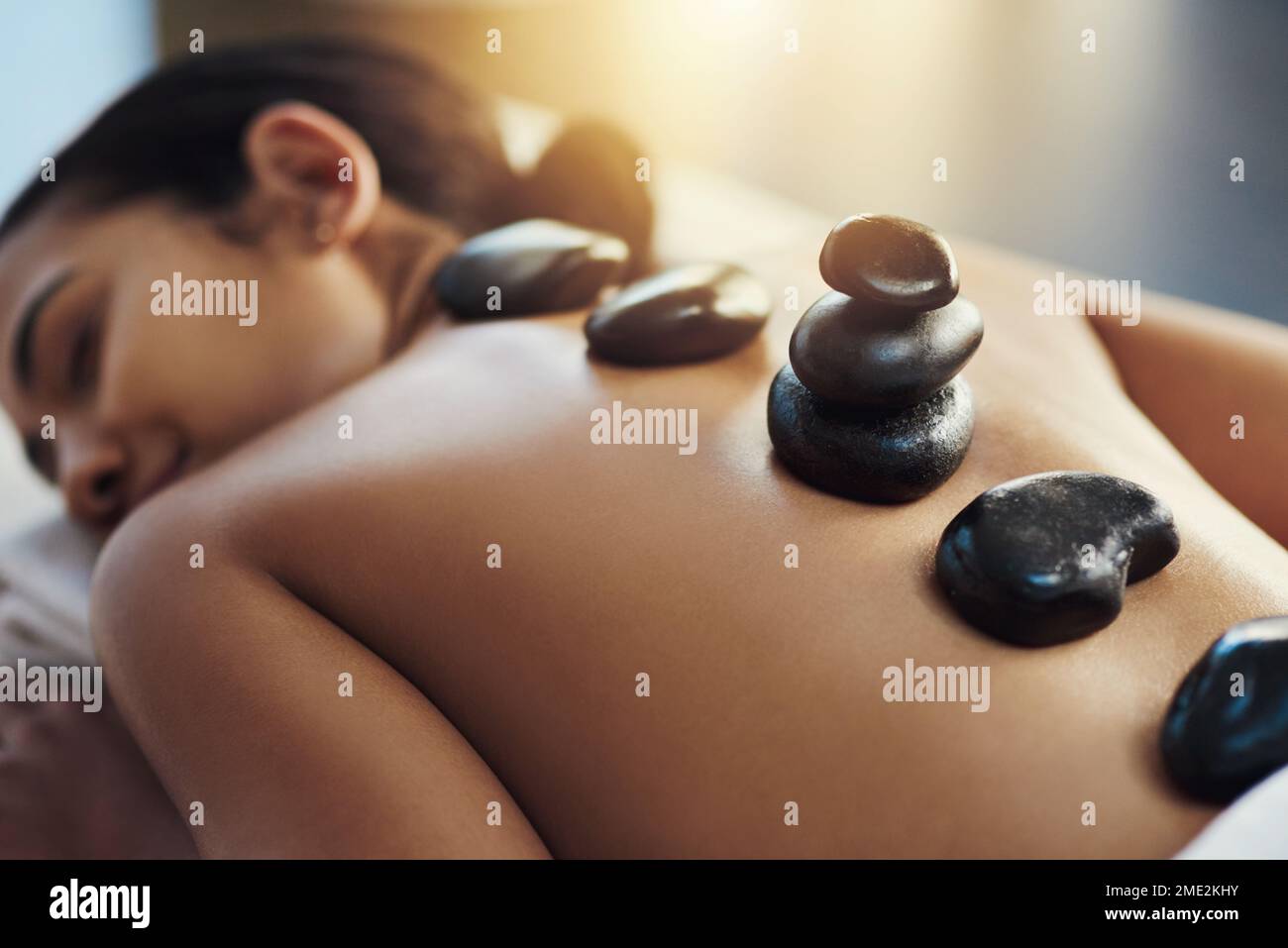 Revitalisiere und heile schmerzende Muskeln. Eine junge Frau, die eine Hot-Stone-Massage in einem Spa bekommt. Stockfoto