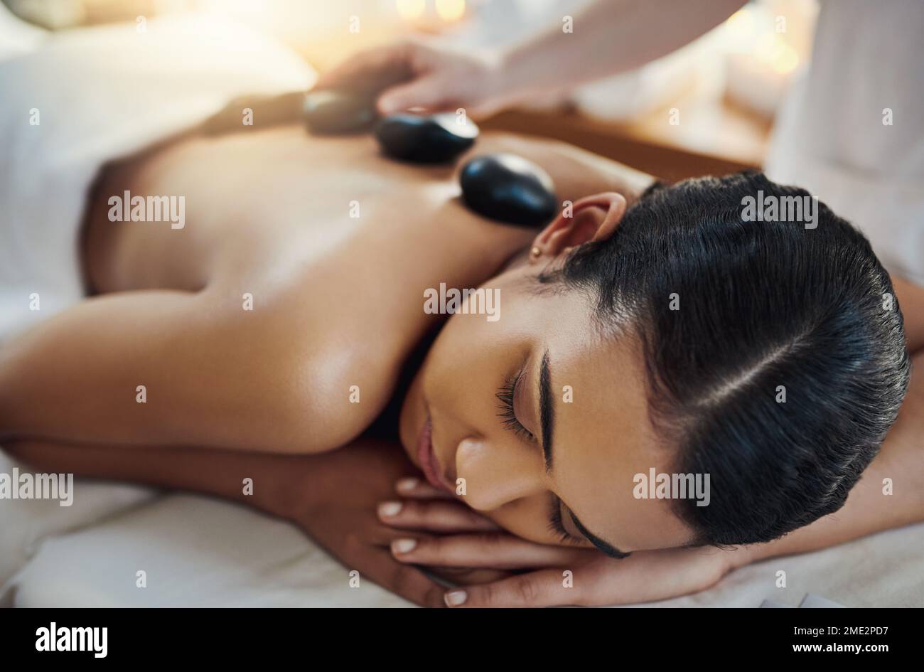 Diese Steine werden deine Spannung abbauen. Eine junge Frau, die eine Hot-Stone-Massage in einem Spa bekommt. Stockfoto