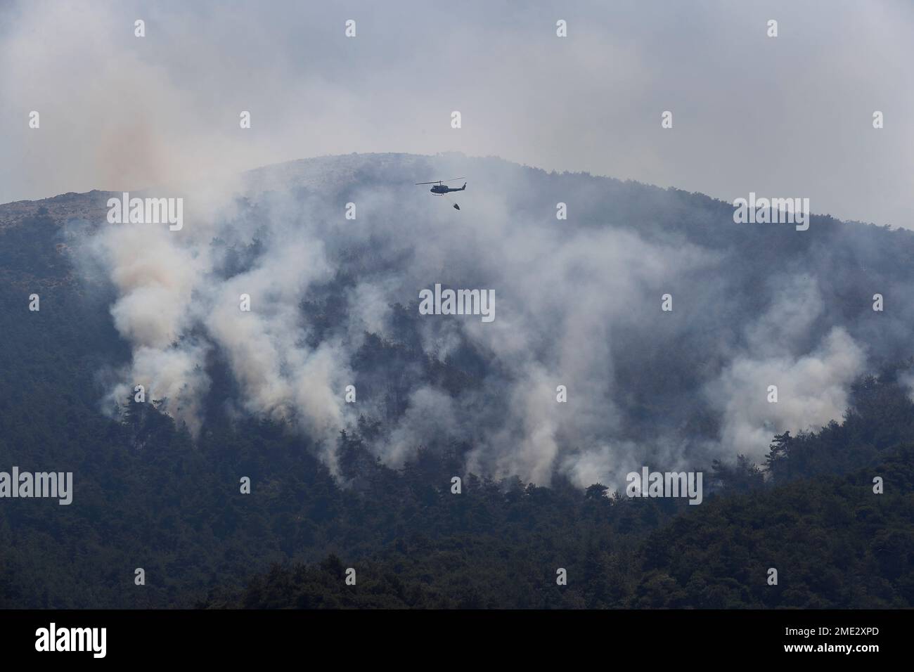 A Lebanese army helicopter flies over a forest fire on an extinguishing