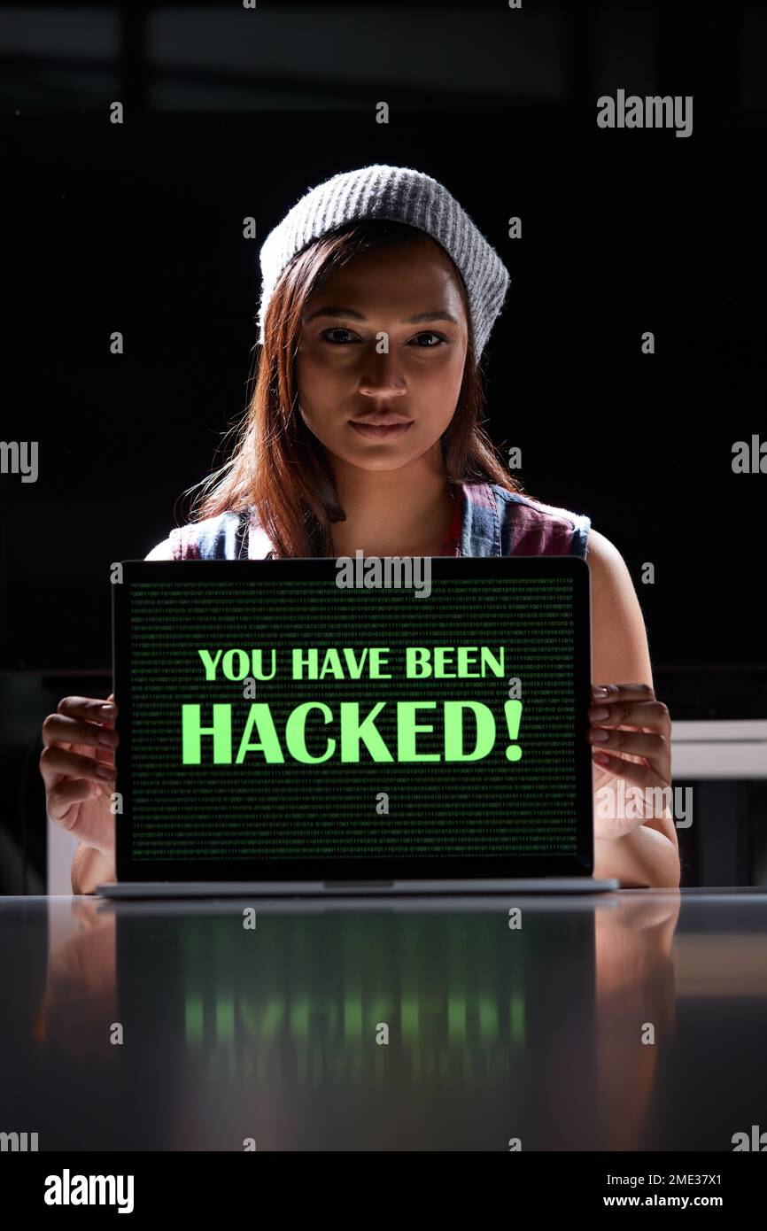 Die zwielichtige Welt der Cyberkriminalität. Eine junge Hackerin, die einen Laptop mit den Worten benutzt, die man auf dem Laptop hackt. Stockfoto