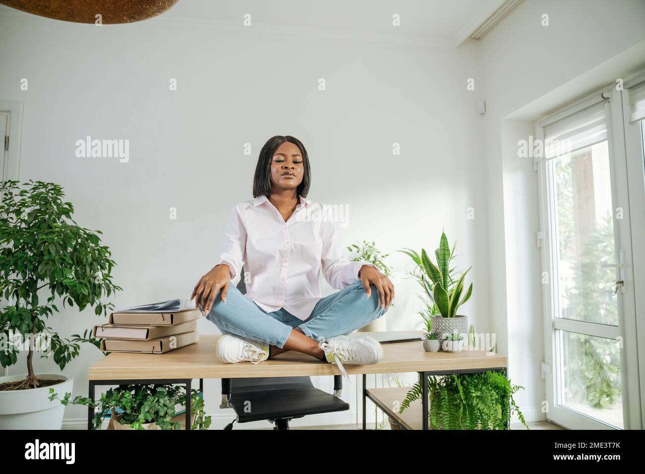 Geschäftsfrau mit geschlossenen Augen meditiert auf dem Schreibtisch im Heimbüro Stockfoto