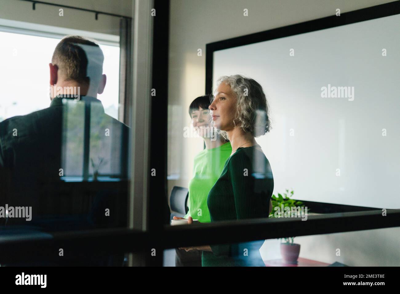Geschäftskollegen in grüner Kleidung, die im Büro stehen Stockfoto