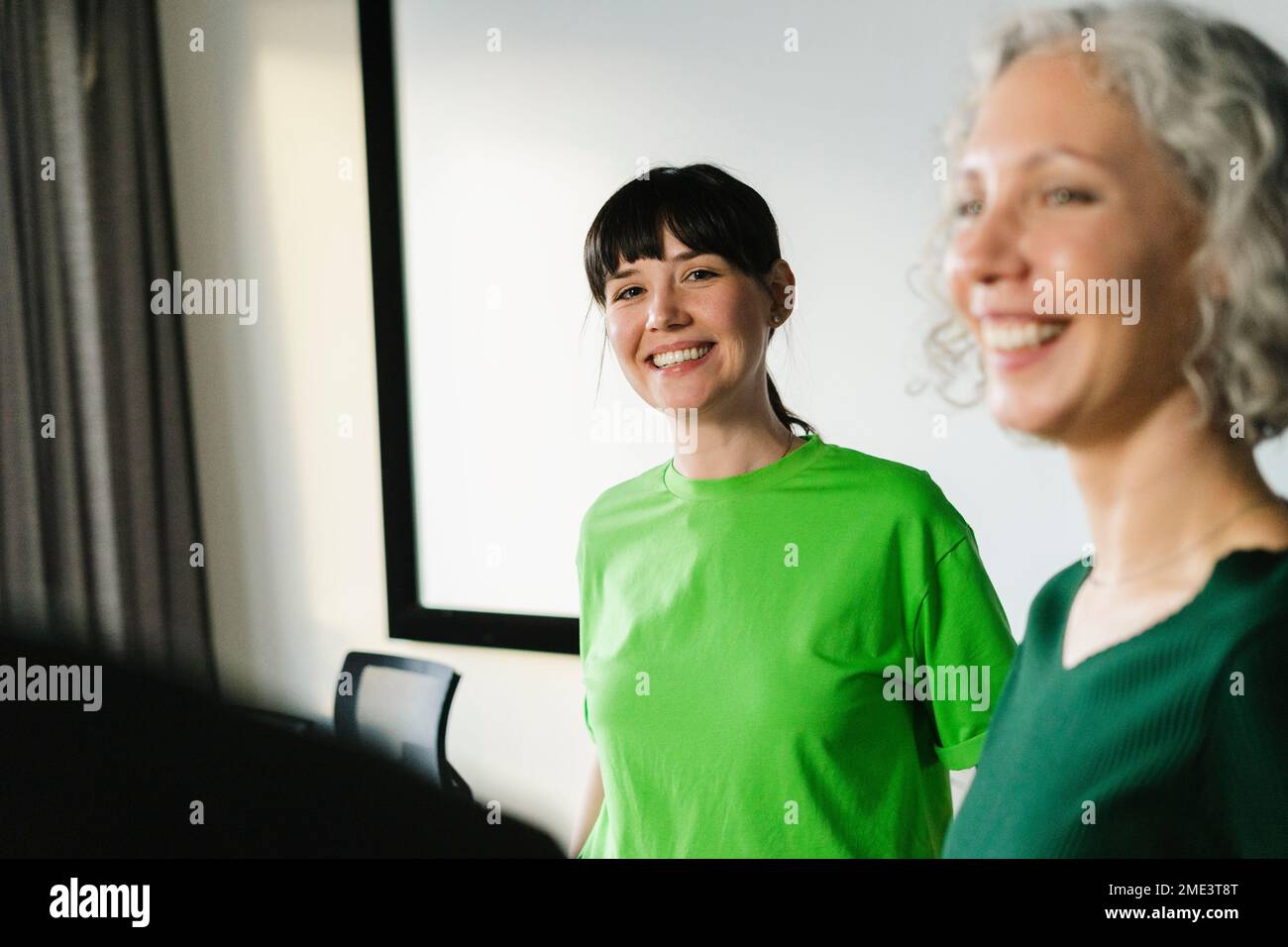 Zwei glückliche Kollegen in grüner Kleidung im Büro Stockfoto