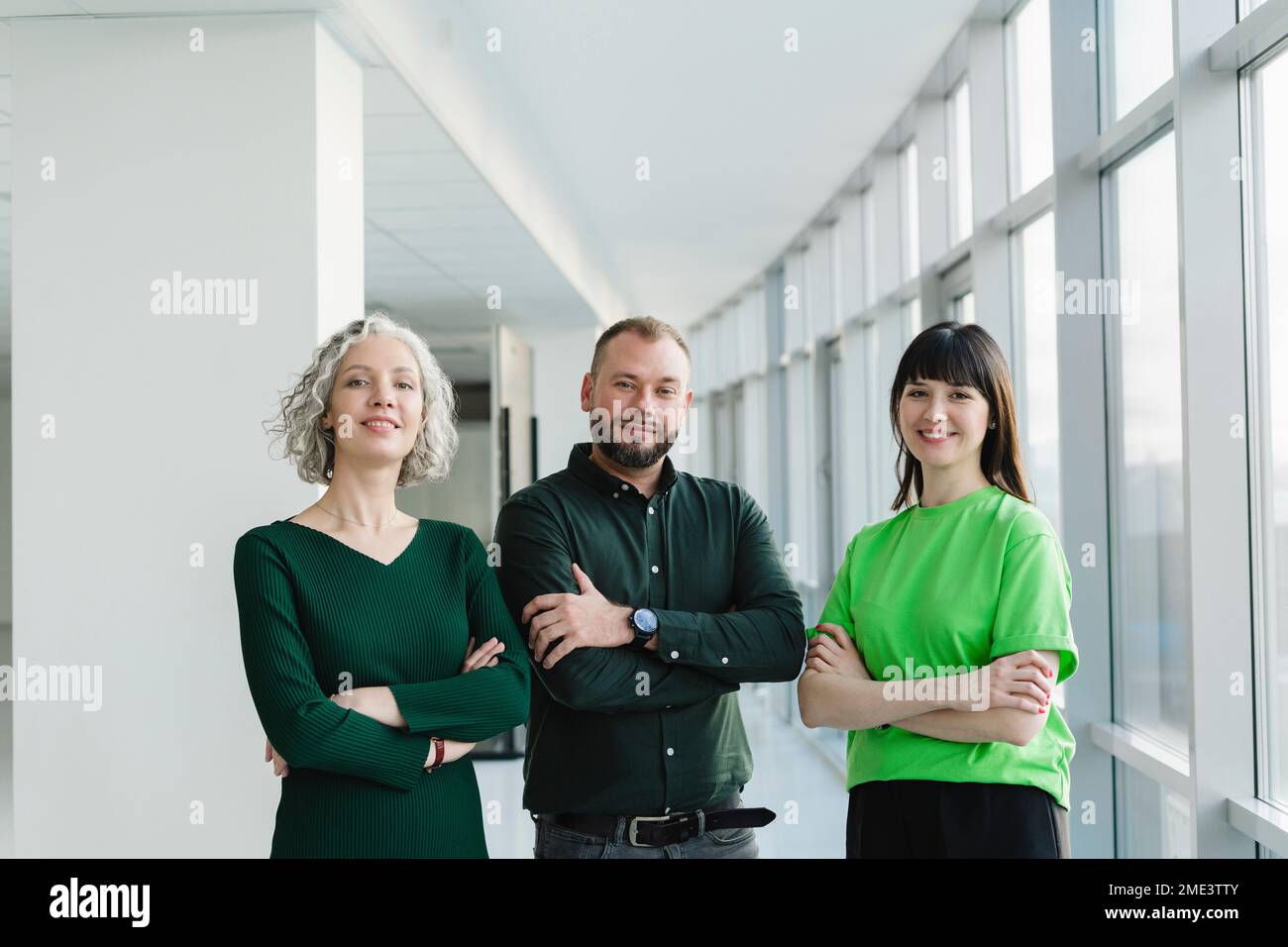 Porträt von drei selbstbewussten Geschäftsleuten in grüner Kleidung auf dem Büroboden Stockfoto
