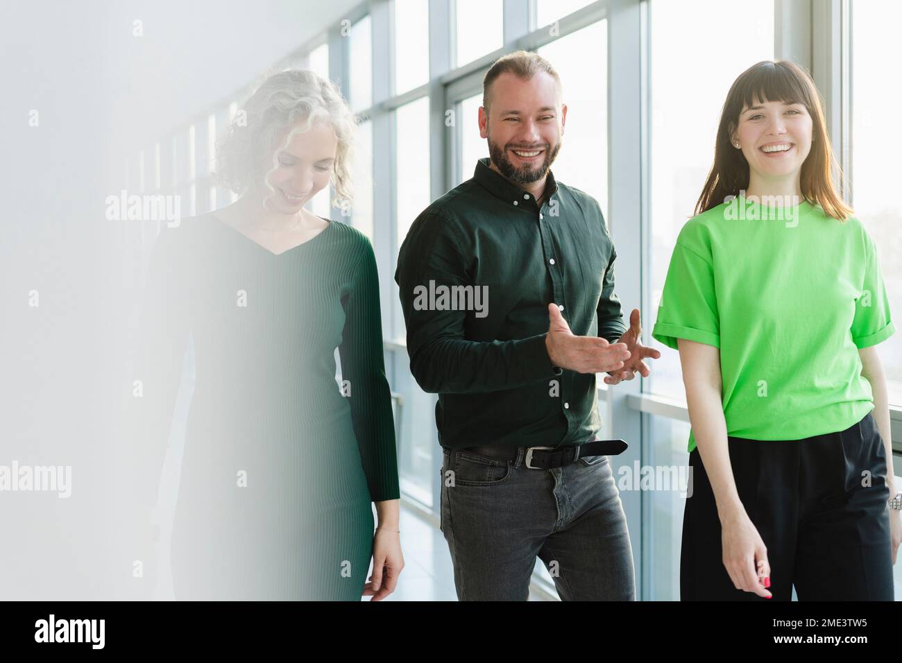 Drei glückliche Geschäftsleute in grüner Kleidung auf dem Büroboden Stockfoto