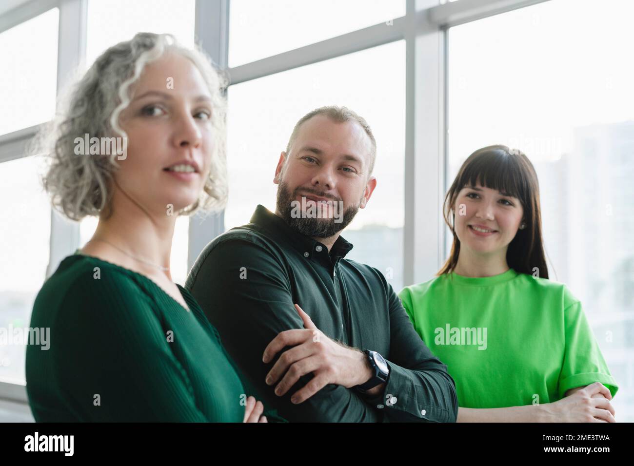 Porträt von drei selbstbewussten Geschäftsleuten in grüner Kleidung auf dem Büroboden Stockfoto