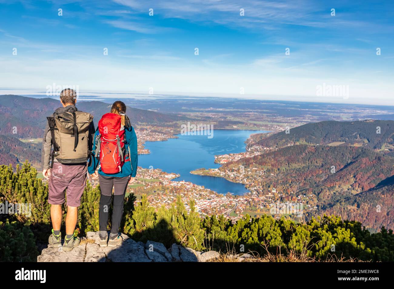 Deutschland, Bayern, Rottach-Egern, Wanderpaar, das den Blick auf den Tegernsee und die umliegenden Städte vom Gipfel des Wallbergs aus bewundert Stockfoto