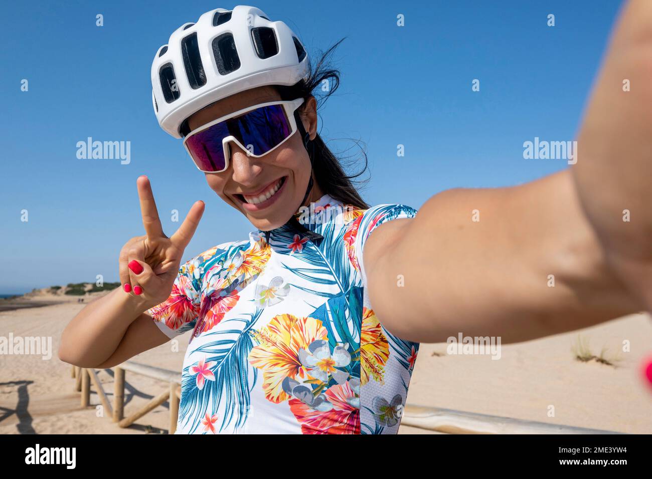 Glücklicher Radfahrer im Helm, der eine friedliche Geste zeigt und Selfie macht Stockfoto