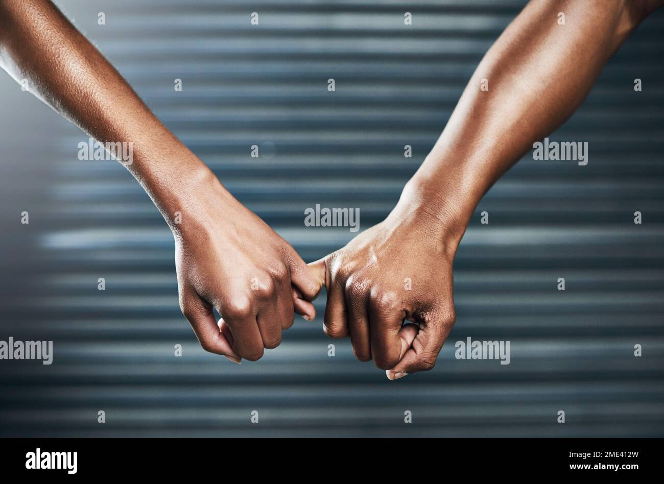 Nun, überstehen Sie das, Seite an Seite. Nahaufnahme eines sportlichen Paares, das sich mit dem kleinen Finger vor grauem Hintergrund hält. Stockfoto