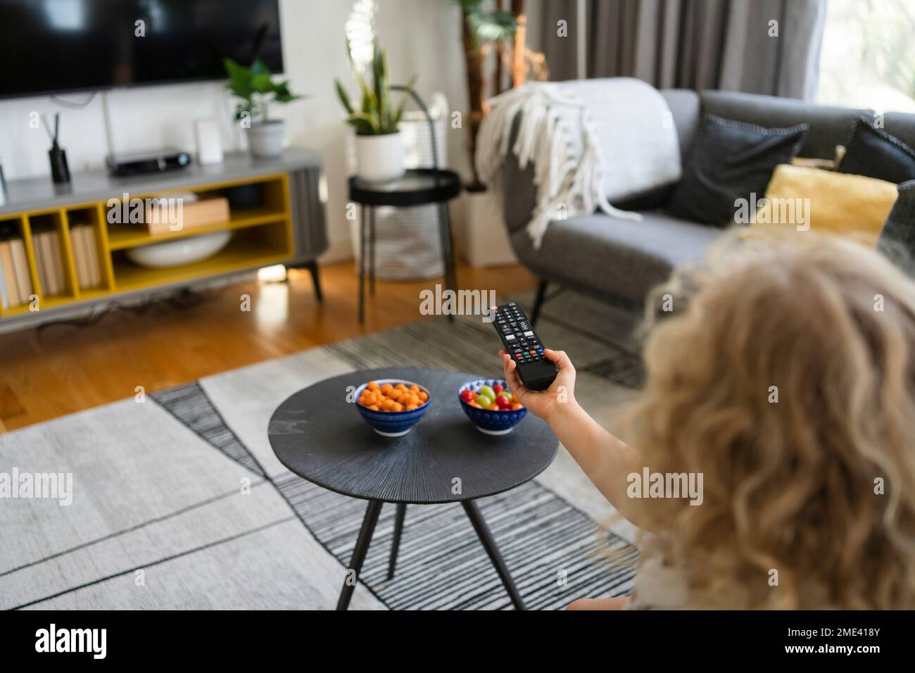 Mädchen, die zu Hause eine TV-Fernbedienung benutzt Stockfoto
