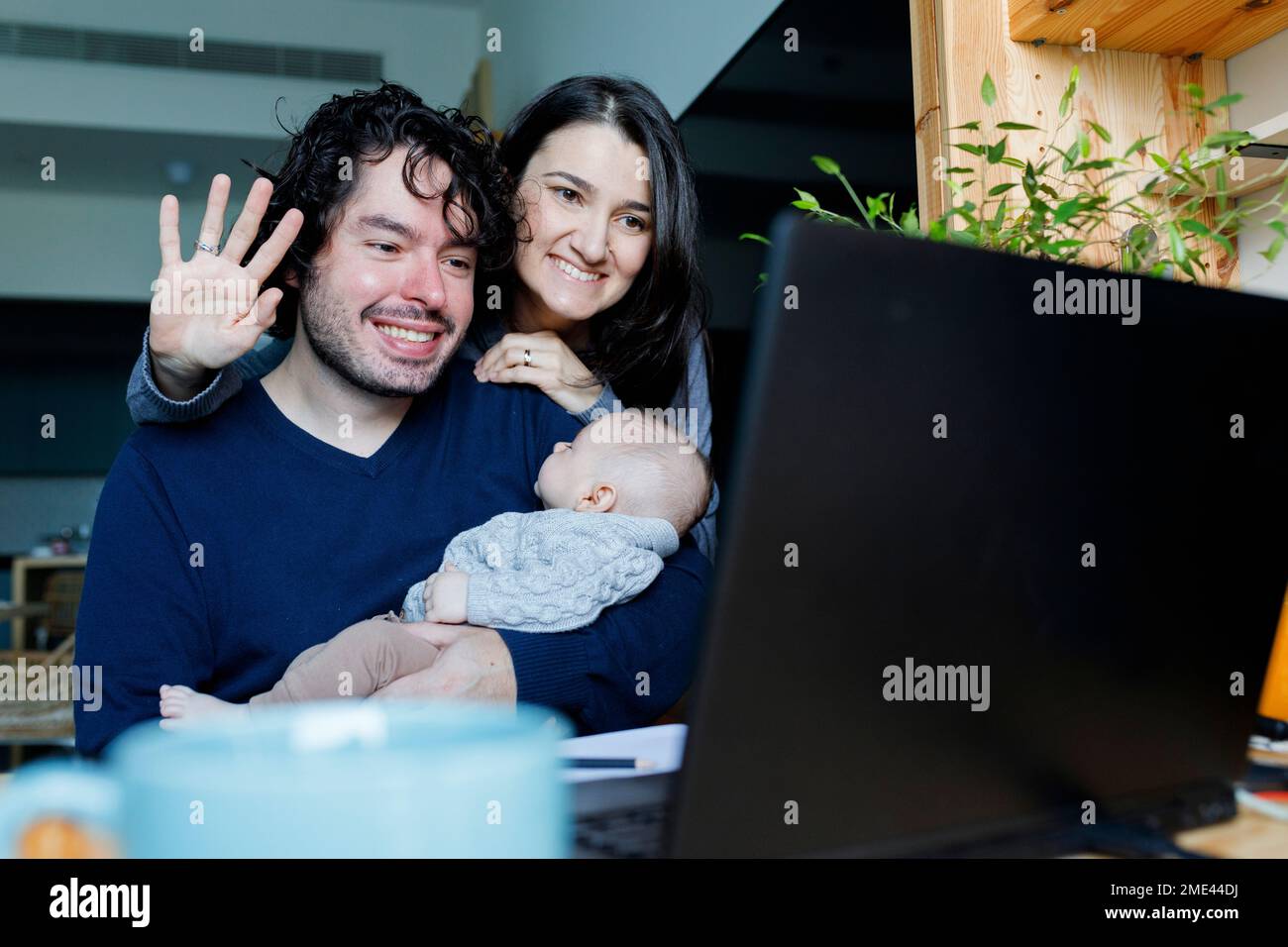 Glücklicher Vater und glückliche Mutter mit einem kleinen Jungen, der per Laptop per Videoanruf telefoniert Stockfoto