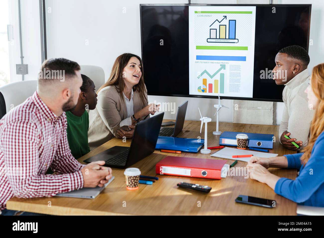 Geschäftsfrau, die mit Kollegen über erneuerbare Energien diskutiert, bei einem Meeting im Büro Stockfoto