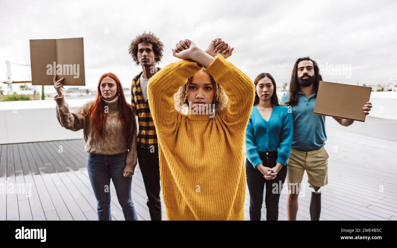 Junge Demonstranten, die Stop-Gesten mit Aktivisten im Hintergrund machen Stockfoto