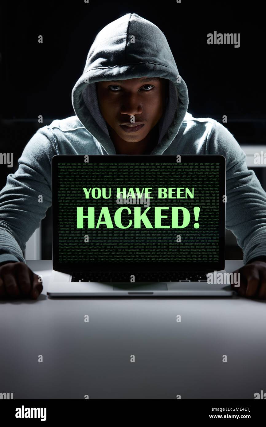 Hüten Sie sich vor den Gefahren von Cyberkriminalität. Ein junger Hacker, der einen Laptop mit den Worten benutzt, die man darauf gehackt hat. Stockfoto
