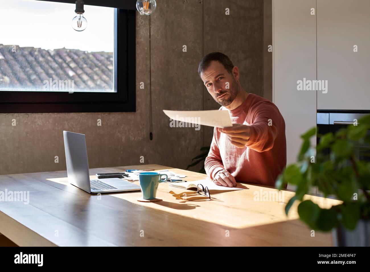 Ein Mann, der zu Hause am Schreibtisch sitzt und die Rechnung zahlt Stockfoto