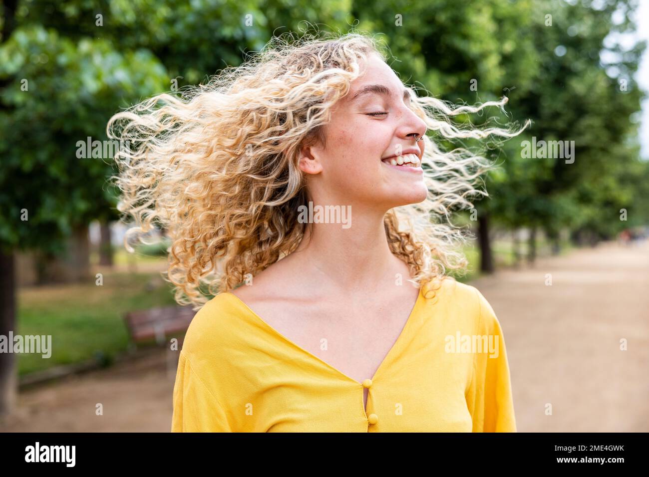 Glückliche junge Frau mit blonden Haaren, die im Park Spaß hat Stockfoto