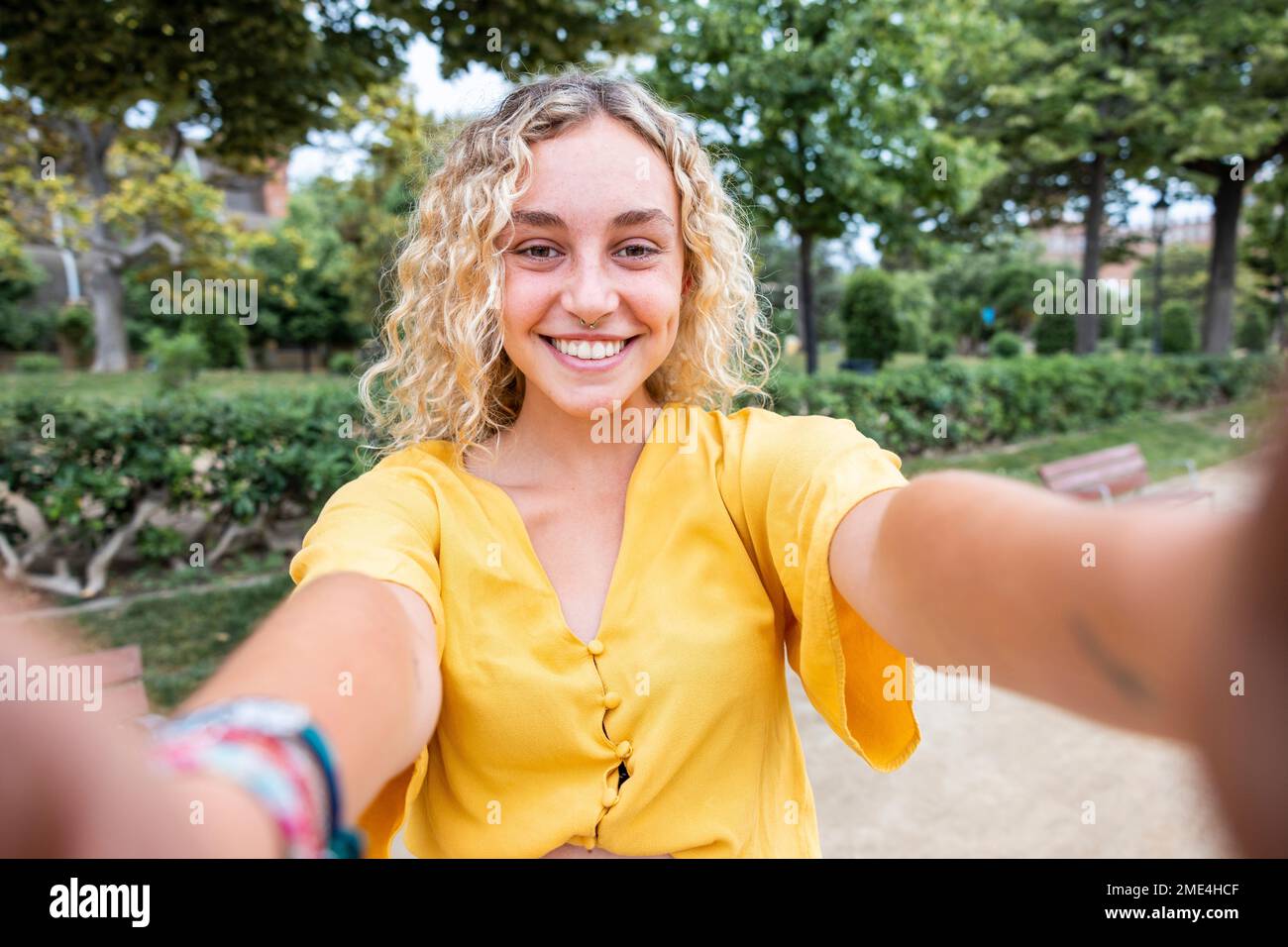 Glückliche junge Frau mit blondem Haar, die Selfie im Park macht Stockfoto
