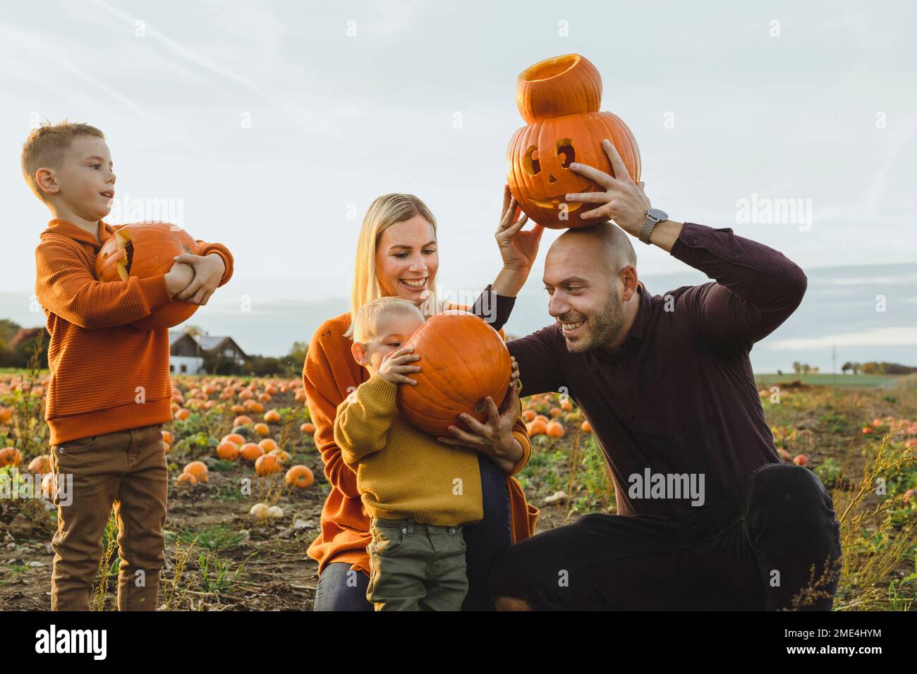 Glückliche Eltern mit Söhnen mit Laternen am Kürbisfeld Stockfoto