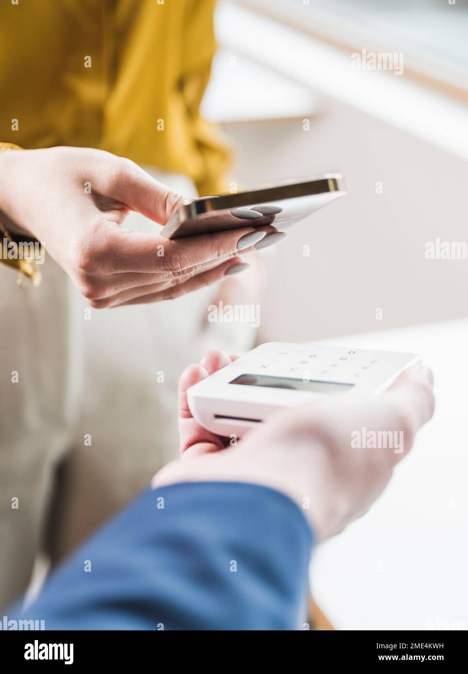 Die Hand einer jungen Geschäftsfrau, die per Smartphone mit einem Kreditkartenleser bezahlt Stockfoto