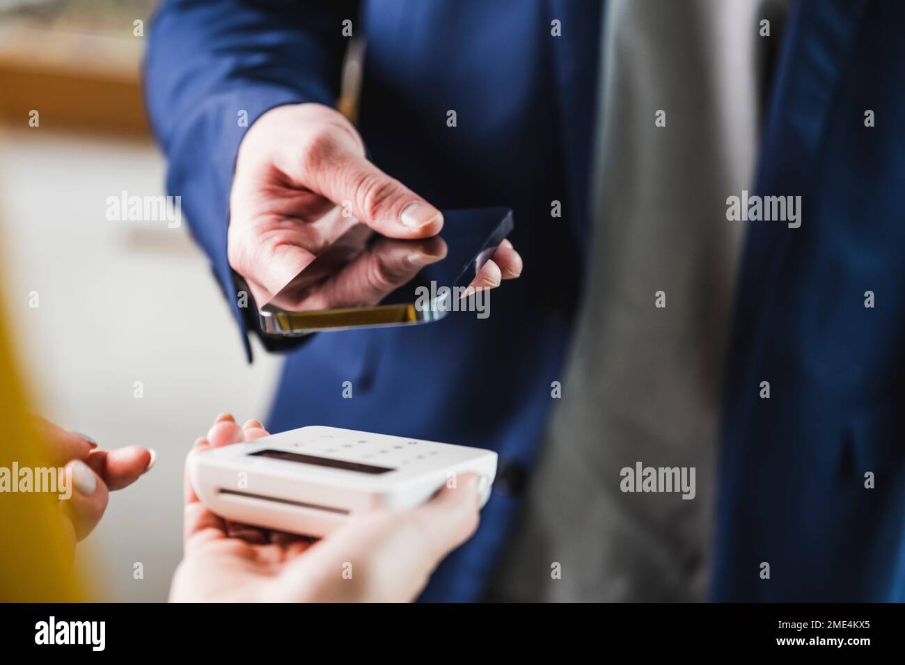 Die Hand eines jungen Geschäftsmannes, der mit dem Smartphone bezahlt Stockfoto