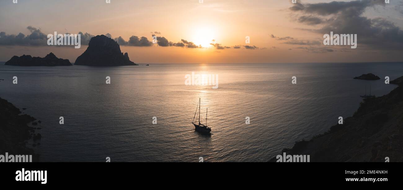 Spanien, Balearen, Segelboot in der Nähe der Küste bei Sonnenuntergang mit Es Vedra im Hintergrund Stockfoto