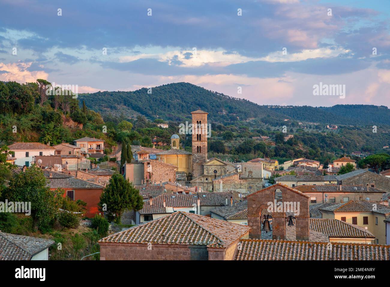 Italien, Latium, Bolsena, Altstadthäuser mit Glockenturm und bewaldetem Hügel im Hintergrund Stockfoto