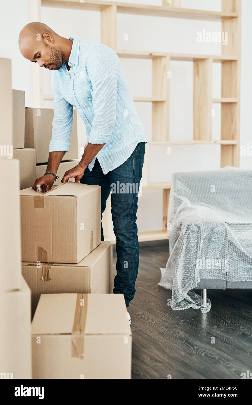 Zeit, sich einzugewöhnen. Ein junger Mann packte beim Umzug aus. Stockfoto