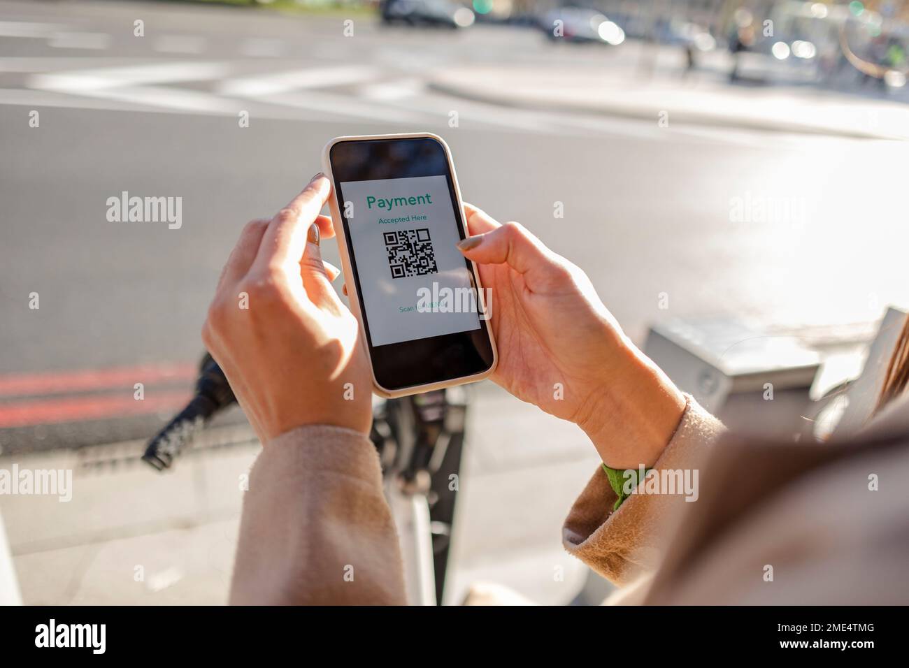 Frau, die kontaktlos mit Smartphone bezahlt, um ein Fahrrad zu mieten Stockfoto