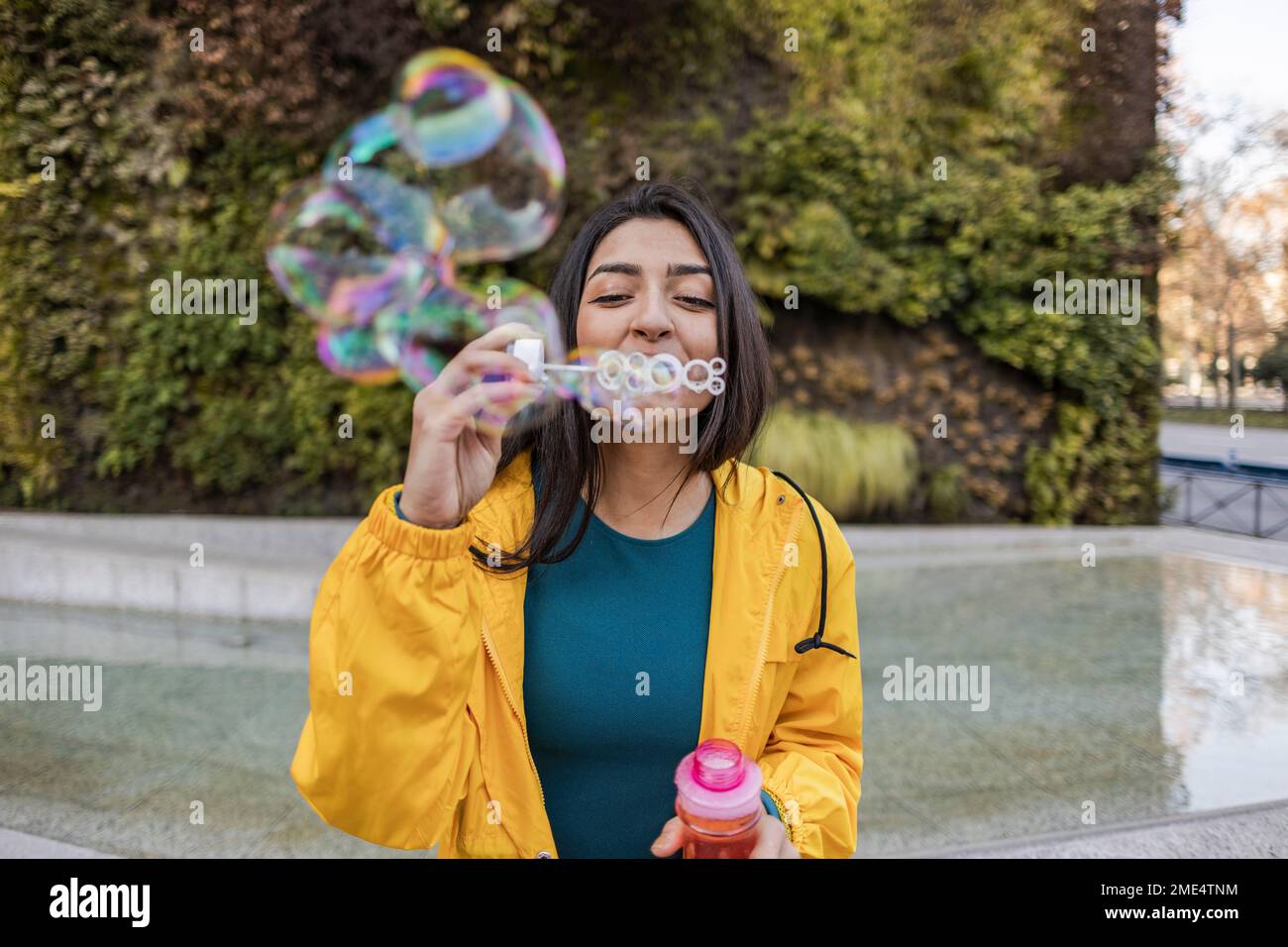 Junge Frau bläst Blasen auf dem Fußweg Stockfoto