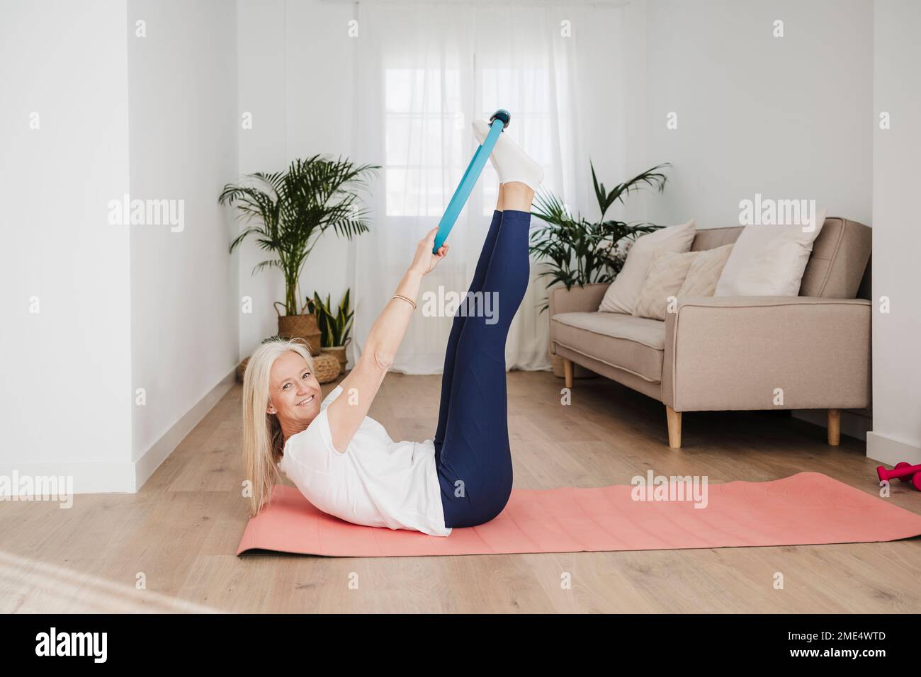 Lächelnde, reife Frau, die mit dem Pilates-Ring trainiert Stockfoto