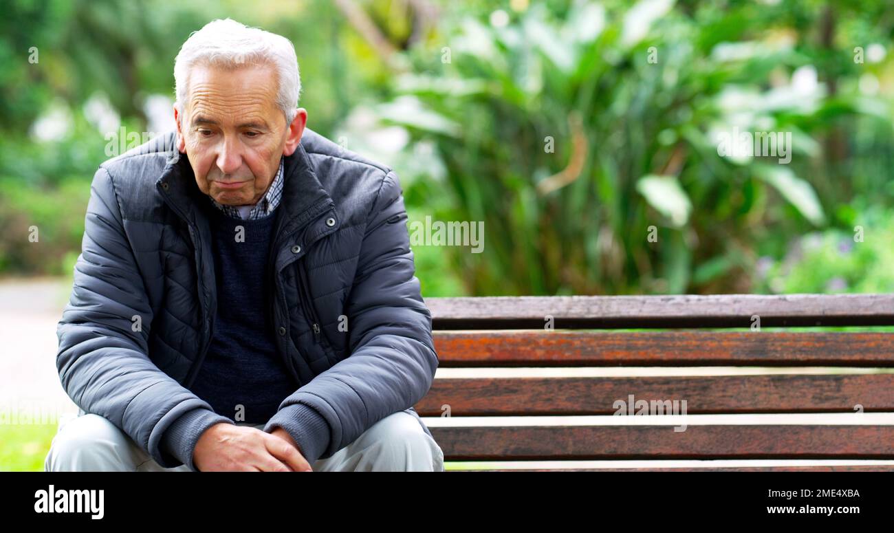 Die Tage werden einsam. Ein sorgenloser alter Mann, der auf einer Bank sitzt, während er im Park im Freien nachdenkt. Stockfoto