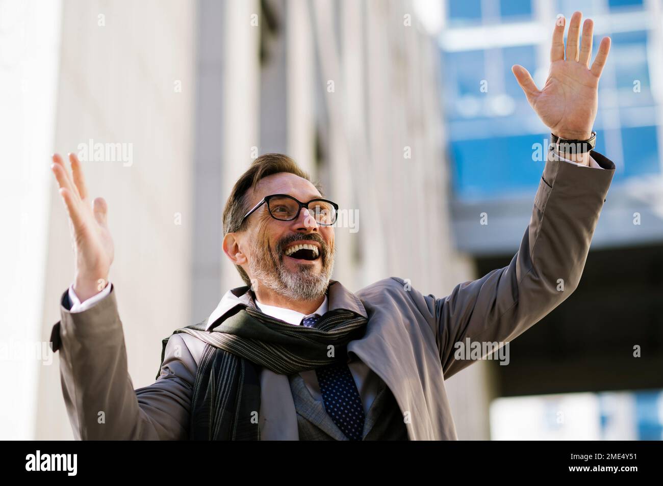 Fröhlicher, reifer Geschäftsmann mit der Hand vor dem Bürogebäude Stockfoto
